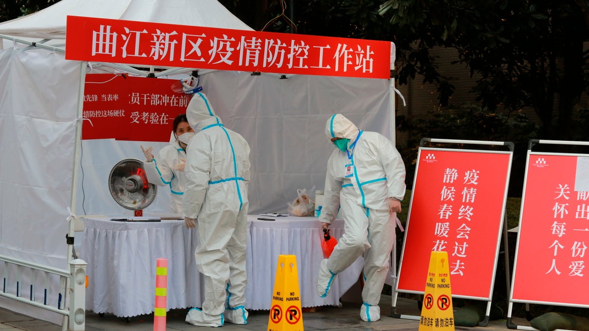 Government workers in protective clothing gather at a work station for pandemic control outside a residential block in Xi'an city in northwest China's Shaanxi province Monday, Jan. 3, 2022. (Chinatopix Via AP) CHINA OUT