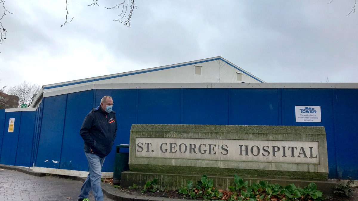 A pedestrian passes a COVID testing facility that has been set up at St.George's Hospital in London, Tuesday, Jan. 4, 2022. (AP Photo/Kirsty Wigglesworth)