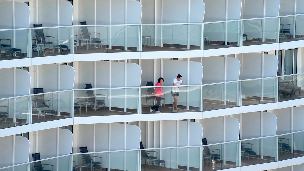 Passengers look out from the Spectrum of the Seas cruise ship docked at Kai Tak cruise terminal in Hong Kong Wednesday, Jan. 5, 2022. (AP Photo/Vincent Yu)