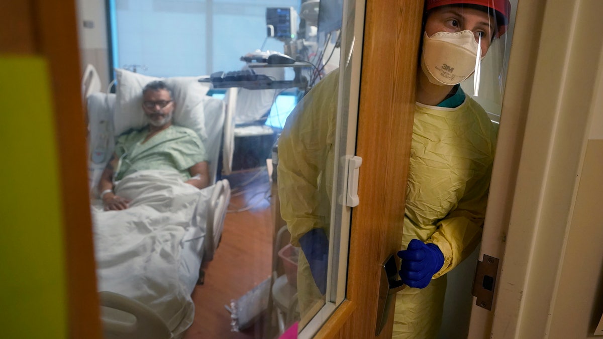 Registered nurse Rachel Chamberlin, of Cornish, N.H., right, steps out of an isolation room where where Fred Rutherford, of Claremont, N.H., left, recovers from COVID-19 at Dartmouth-Hitchcock Medical Center, in Lebanon, N.H. (AP Photo/Steven Senne)