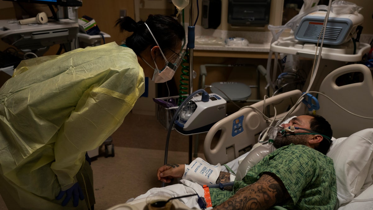 Registered nurse Emily Yu, left, talks to Paul Altamirano, a 50-year-old COVID-19 patient, at Providence Holy Cross Medical Center in Los Angeles, Dec. 13, 2021. (AP Photo/Jae C. Hong, File)