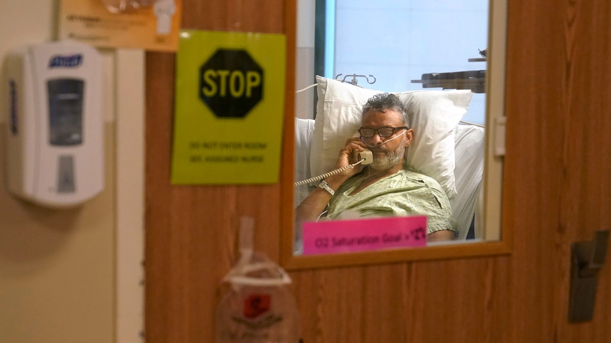 Patient Fred Rutherford, of Claremont, N.H., who is recovering from COVID-19, speaks on a telephone with a reporter from The Associated Press from an isolation room at Dartmouth-Hitchcock Medical Center, in Lebanon, N.H. (AP Photo/Steven Senne)