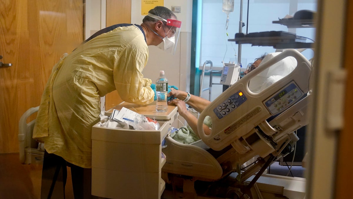 Edward Merrens, chief clinical officer at Dartmouth-Hitchcock Health, visits COVID-19 patient Fred Rutherford, of Claremont, N.H., right, at Dartmouth-Hitchcock Medical Center, in Lebanon, N.H., Monday, Jan. 3, 2022. Hospitals like this medical center, the largest in New Hampshire, are overflowing with severely ill, unvaccinated COVID-19 patients from northern New England. If he returns home, he said, Rutherford promises to get vaccinated and tell others to do so, too. (AP Photo/Steven Senne)