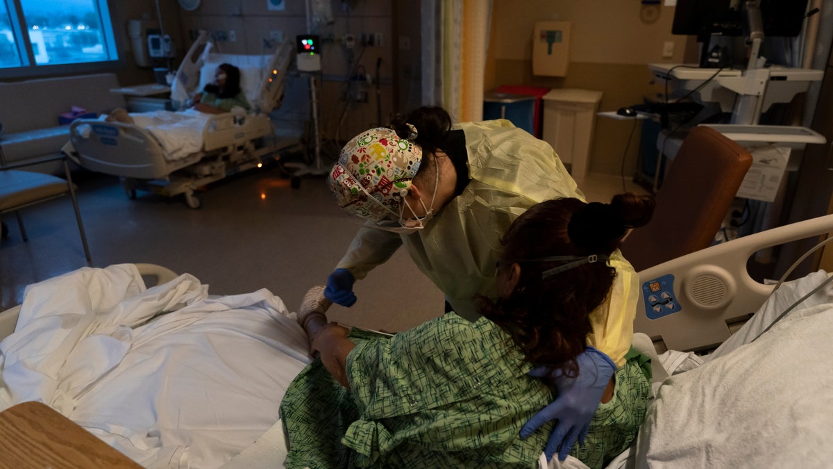 Registered nurse Nvard Termendzhyan helps Linda Calderon, a 71-year-old COVID-19 patient, sit up at Providence Holy Cross Medical Center in Los Angeles. (AP Photo/Jae C. Hong, File)