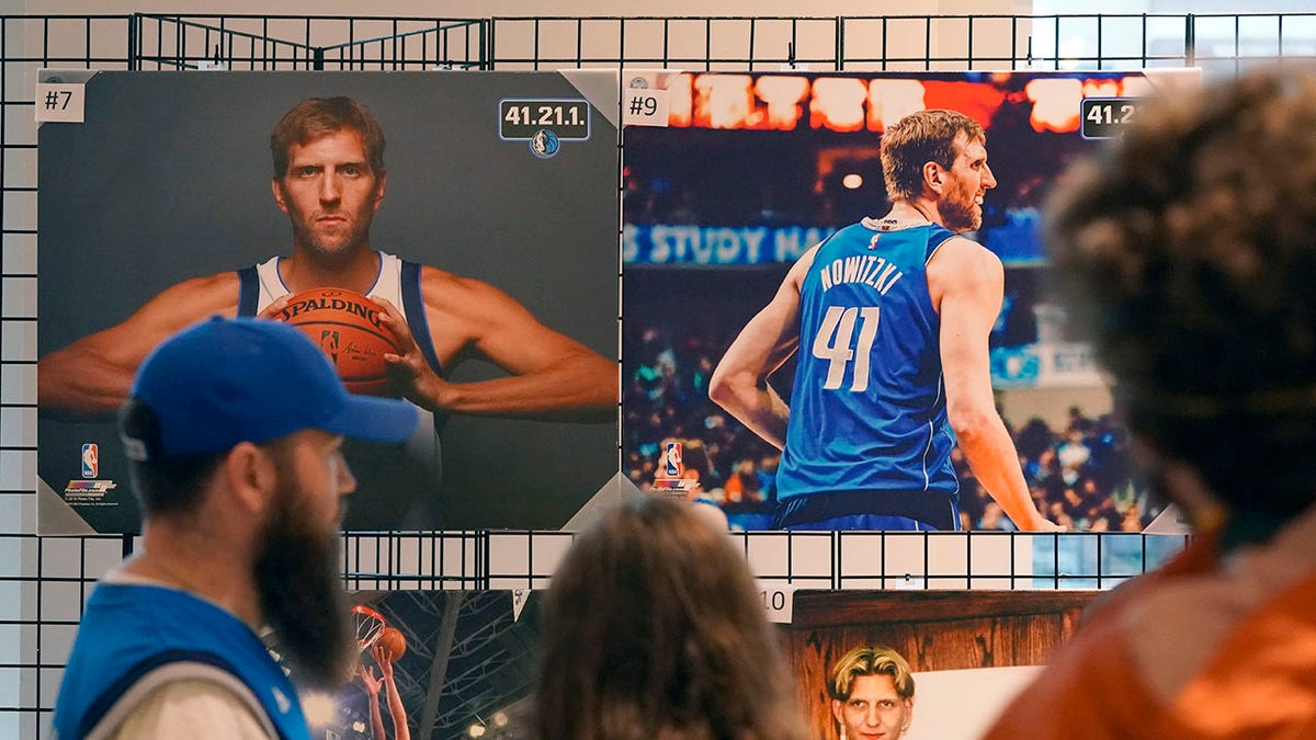 People stand in line to buy memorabilia of former Dallas Mavericks Dirk Nowitzki before an NBA basketball game between the Golden State Warriors and Dallas Mavericks in Dallas, Wednesday, Jan. 5, 2022. The Mavericks are retiring Nowitzki's number in a ceremony after the game.