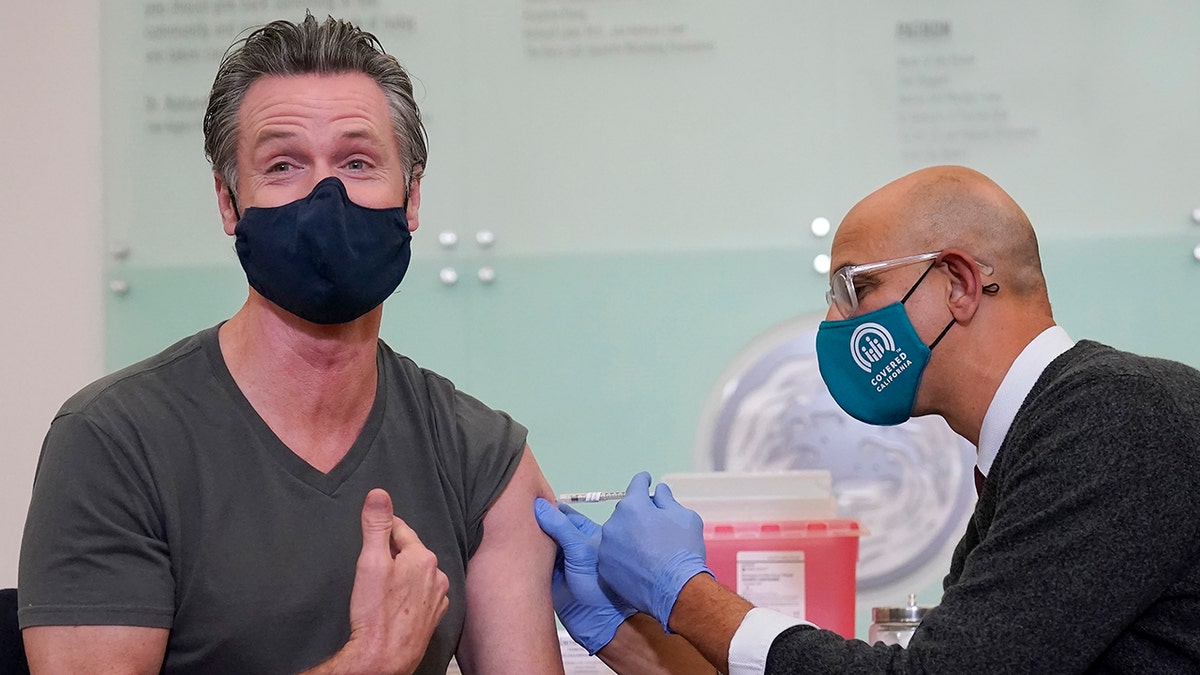 California Gov. Gavin Newsom, left, receives a Moderna COVID-19 vaccine booster shot from California Health and Human Services Secretary Dr. Mark Ghaly at Asian Health Services in Oakland, California, on Oct. 27, 2021. 