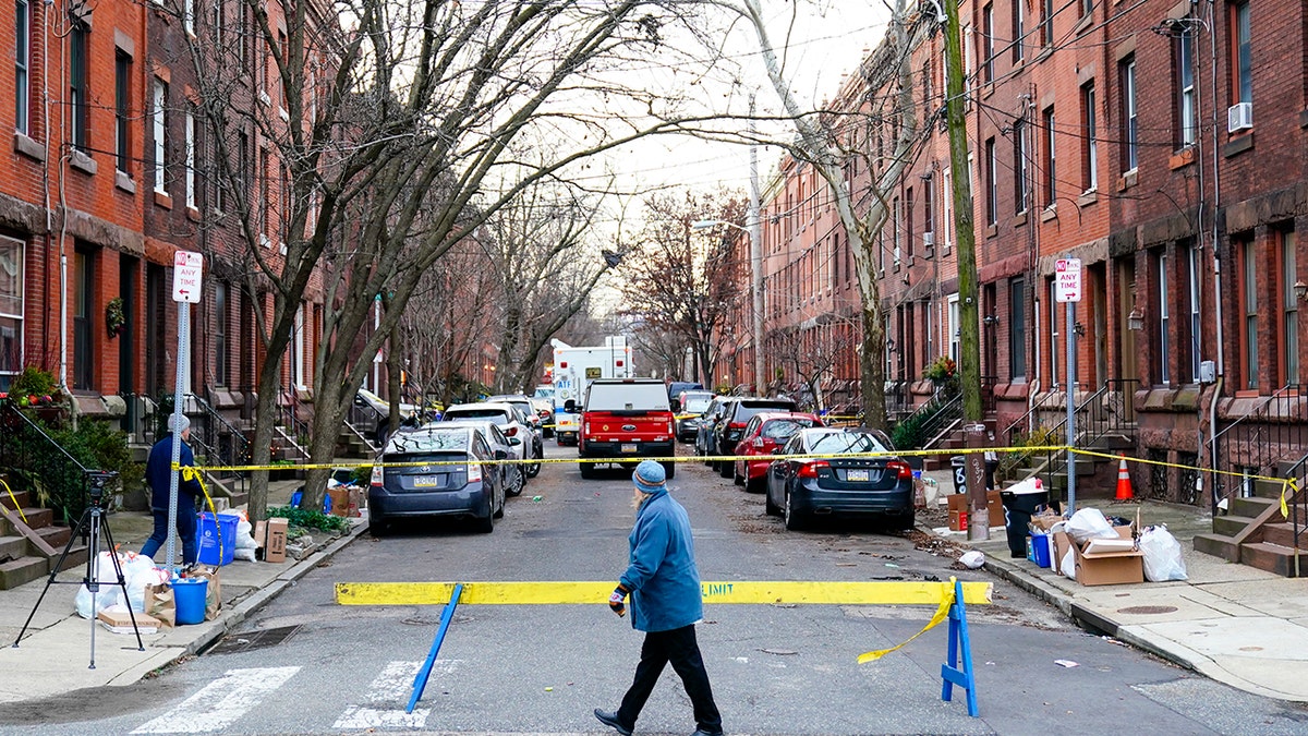 A passer-by looks over the barricade on the street of Wednesday's deadly fire in the Fairmount neighborhood of Philadelphia on Thursday, Jan. 6, 2022. (AP Photo/Matt Rourke)