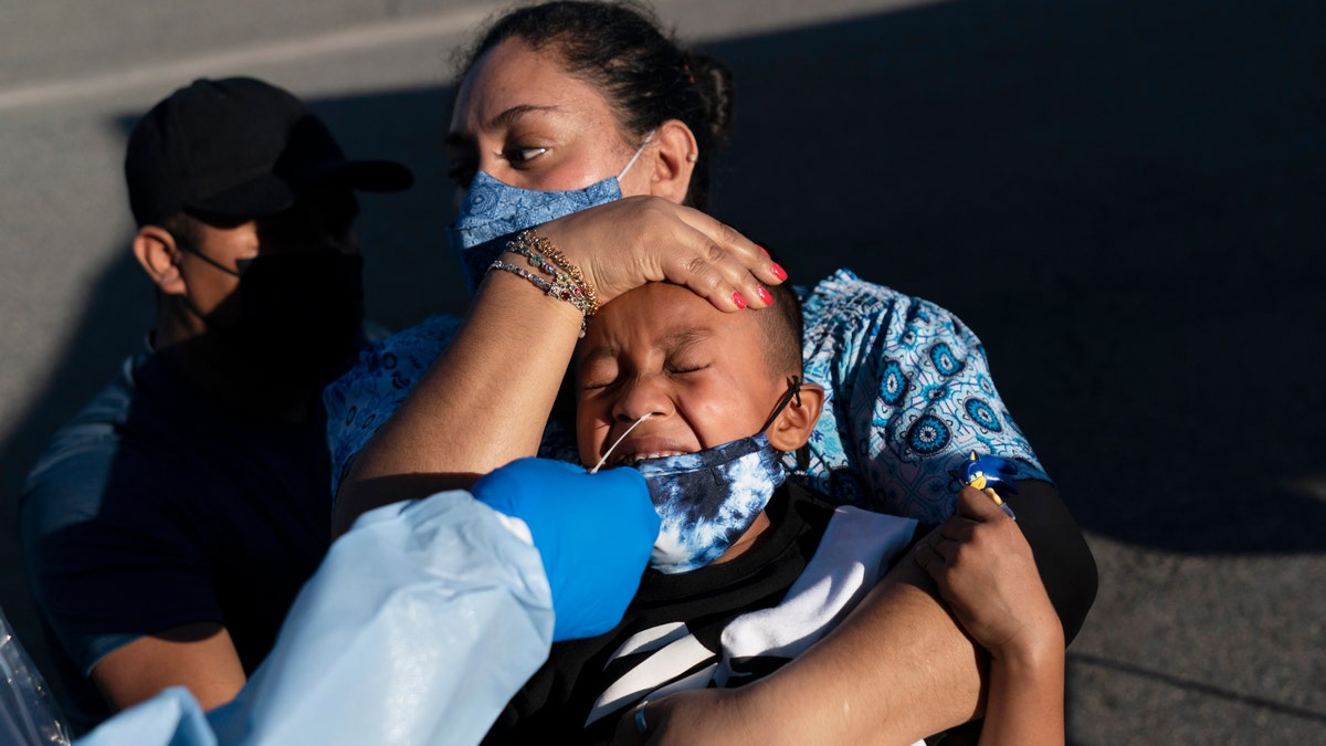 Reina Monterrosa holds the head of her 6-year-old son, Anderson, as nurse practitioner Rita Ray collects a nasal swab sample for a COVID-19 test at Families Together of Orange County community health center in Tustin, Calif., Thursday, Jan. 6, 2022. (AP Photo/Jae C. Hong)
