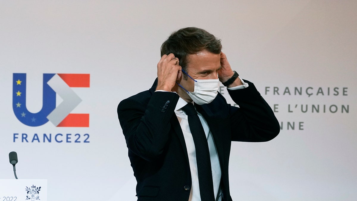 French President Emmanuel Macron puts on his protective mask after participating in a media conference with European Commission President Ursula von der Leyen at the Elysee Palace in Paris, France, Friday, Jan. 7, 2022. (AP Photo/Michel Euler, Pool)