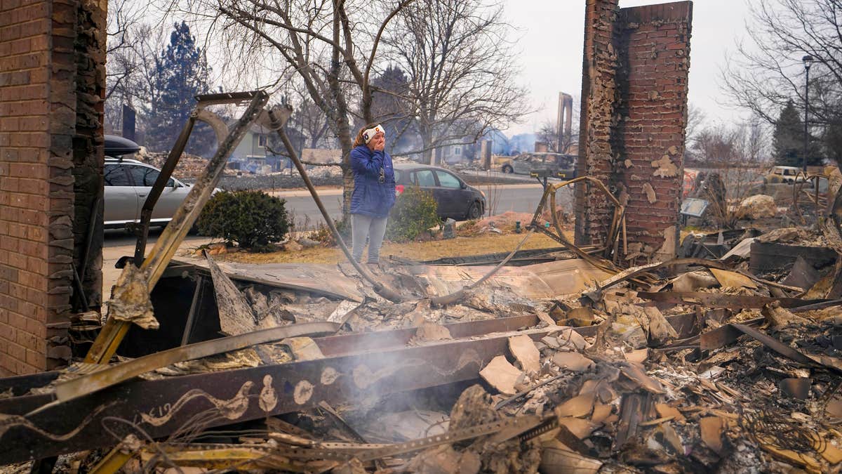 A woman reacts to seeing the remains of her mother's home destroyed by the Marshall Wildfire in Louisville, Colo., Dec. 31, 2021. (AP Photo/Jack Dempsey, File)