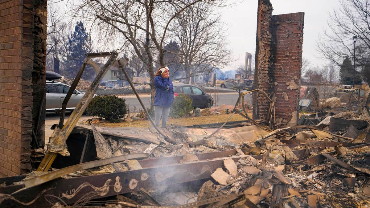 A woman reacts to seeing the remains of her mother's home destroyed by the Marshall Wildfire in Louisville, Colo., Dec. 31, 2021. (AP Photo/Jack Dempsey, File)