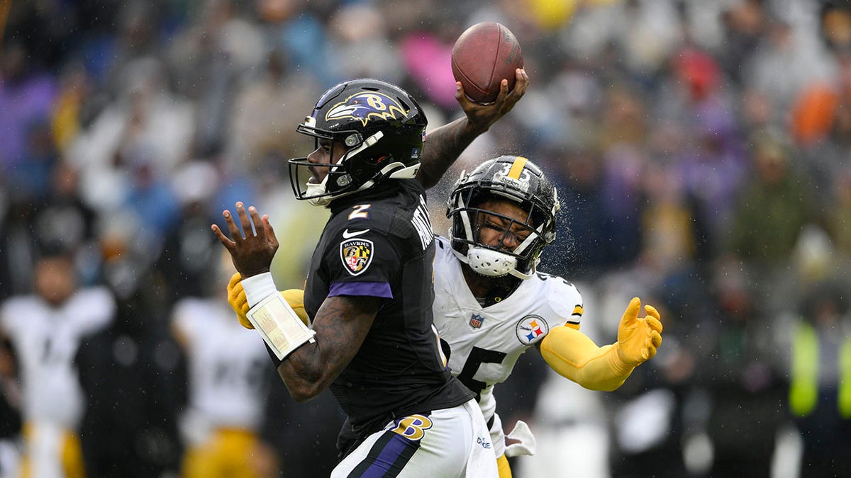 Water sprays off the helmet of Pittsburgh Steelers cornerback Arthur Maulet, right, as he prepares to make a hit on Baltimore Ravens quarterback Tyler Huntley during the first half of an NFL football game, Sunday, Jan. 9, 2022, in Baltimore.