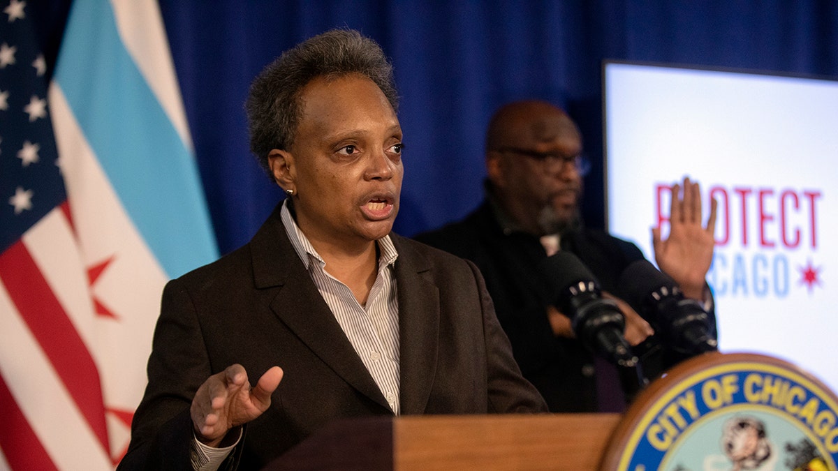 Lori Lightfoot in a suit gesturing before a podium