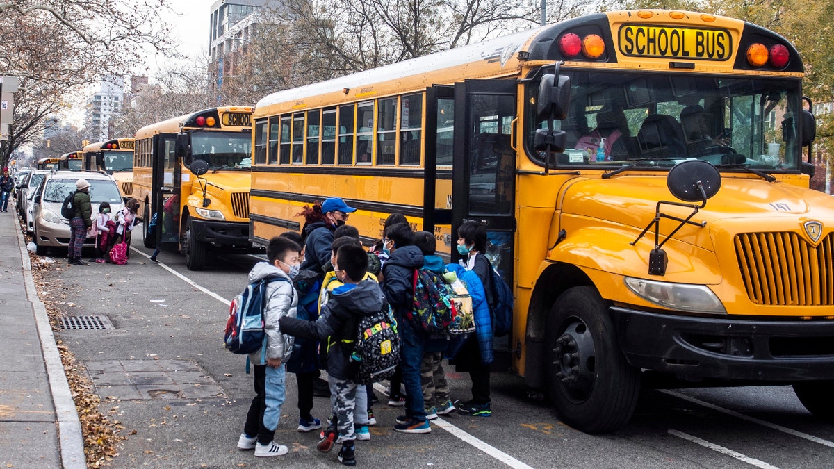 Students wearing masks board a school bus outside New Explorations into Science, Technology and Math school, in the Lower East Side neighborhood of New York, Dec. 21, 2021. In a reversal, New York Mayor Eric Adams is considering a remote option for schools. (AP Photo/Brittainy Newman, File)