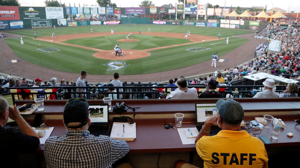 Ron Besaw, right, operates a laptop computer as home plate umpire Brian deBrauwere gets signals from radar with the ball and strikes calls during the fourth inning of the Atlantic League All-Star minor league baseball game in York, Pennsylvania, July 10, 2019.