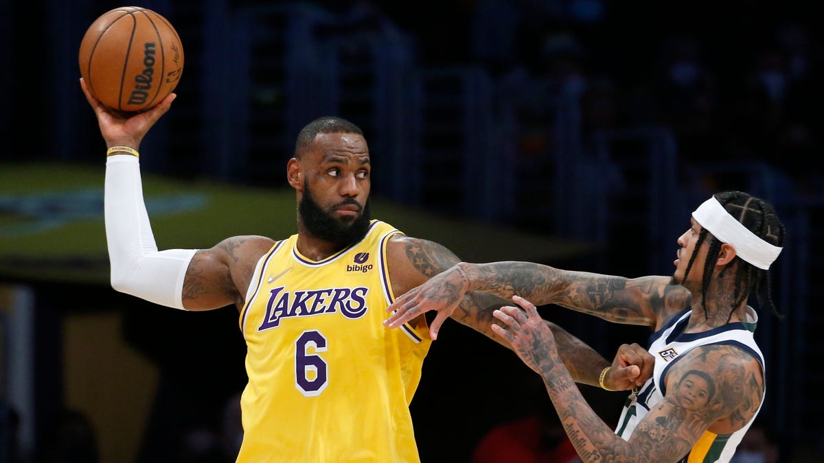 Los Angeles Lakers forward LeBron James (6) is defended by Utah Jazz guard Jordan Clarkson, right, during the first half of an NBA basketball game in Los Angeles, Monday, Jan. 17, 2022. 