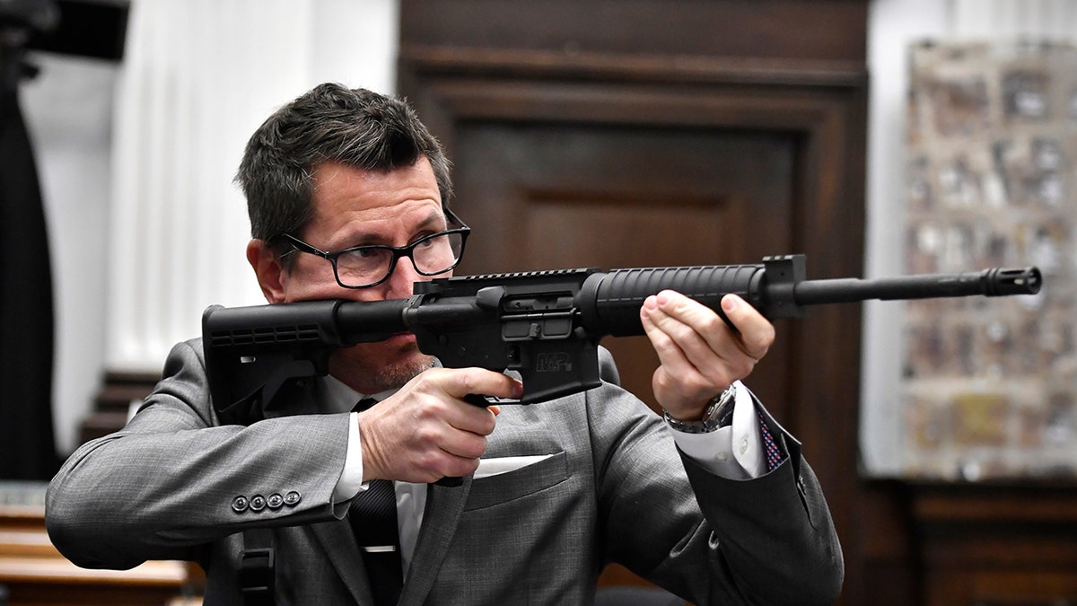 Assistant District Attorney Thomas Binger holds Kyle Rittenhouse's gun as he gives the state's closing argument in Kyle Rittenhouse's trial at the Kenosha County Courthouse in Kenosha, Wisconsin, on Monday, Nov. 15, 2021.