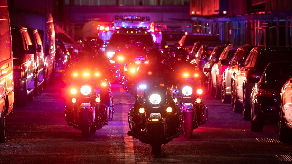 NYPD officers in motorcycles lead an ambulance
