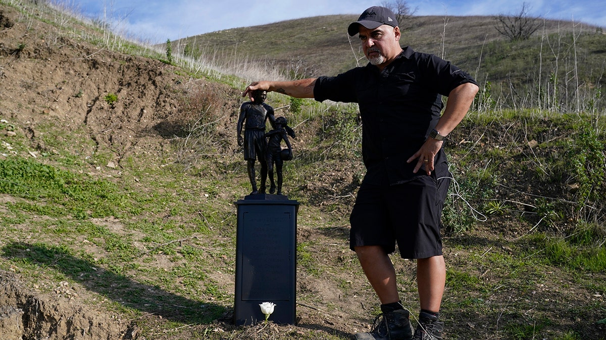 Dan Medina stands next to a statue he created in memory of former Los Angeles Lakers NBA basketball player Kobe Bryant and his daughter, Gianna, on Wednesday, Jan. 26, 2022, in Calabasas, Calif. 