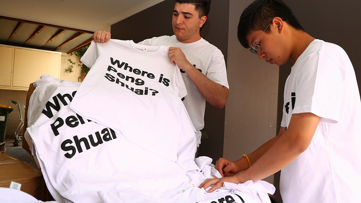 Drew Pavlou, left, and Max Mok show some of the 1,000 shirts they plan to hand out to patrons ahead of Saturday's women's singles final at the Australian Open tennis championships in Melbourne, Australia, Friday, Jan. 28, 2022.