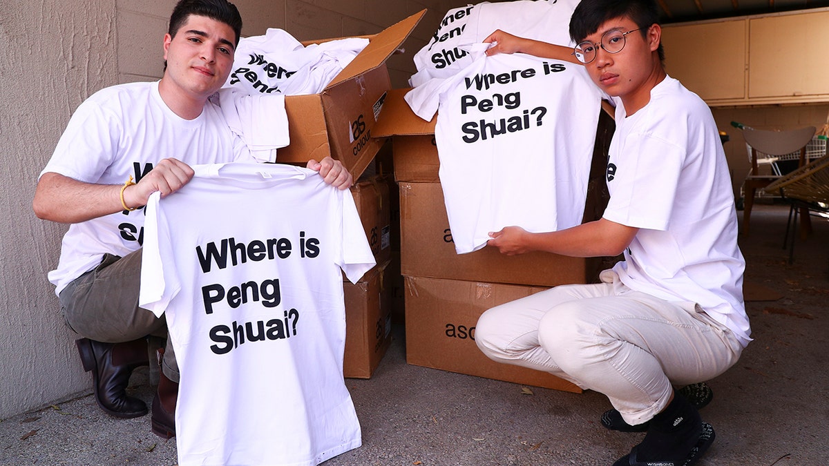 Drew Pavlou, left, and Max Mok show some of the 1,000 shirts they plan to hand out to patrons ahead of Saturday's women's singles final at the Australian Open tennis championships in Melbourne, Australia, Friday, Jan. 28, 2022. 