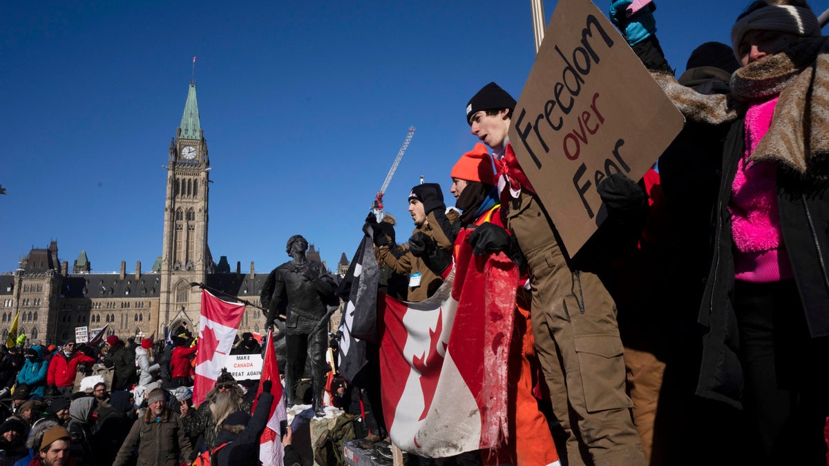 Protesters participating in a cross-country truck convoy protesting measures taken by authorities to curb the spread of COVID-19 and vaccine mandates gather near Parliament Hill in Ottawa on Saturday, Jan. 29, 2022. (Adrian Wyld/The Canadian Press via AP)