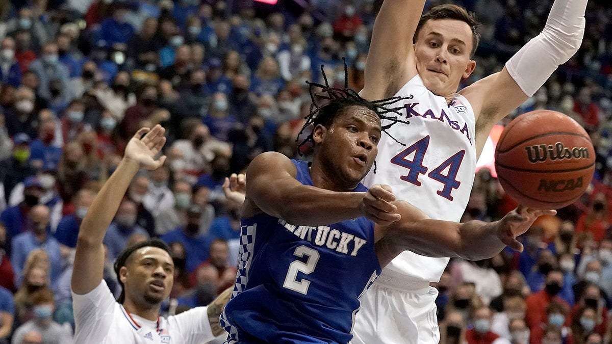 Kentucky guard Sahvir Wheeler (2) passes under pressure from Kansas forward Mitch Lightfoot (44) and guard Bobby Pettiford (0) during the second half of an NCAA college basketball game Saturday, Jan. 29, 2022, in Lawrence, Kan. Kentucky won 80-62.