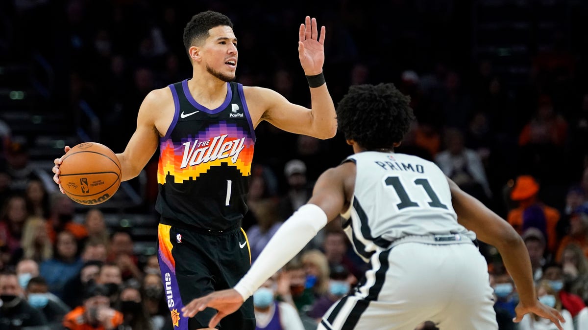 Phoenix Suns guard Devin Booker (1) calls a play as San Antonio Spurs guard Joshua Primo (11) defends during the second half of an NBA basketball game, Sunday, Jan. 30, 2022, in Phoenix. The Suns defeated the Spurs 115-110. 