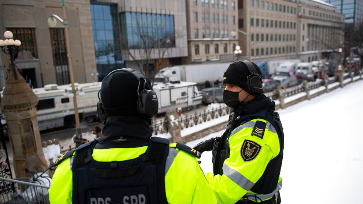 Parliamentary Protective Service officers wear headsets for hearing protection against the sound of truck horns as a rally against COVID-19 restrictions, which began as a cross-country convoy protesting a federal vaccine mandate for truckers, continues in Ottawa, on Monday, Jan. 31, 2022. (Justin Tang/The Canadian Press via AP)