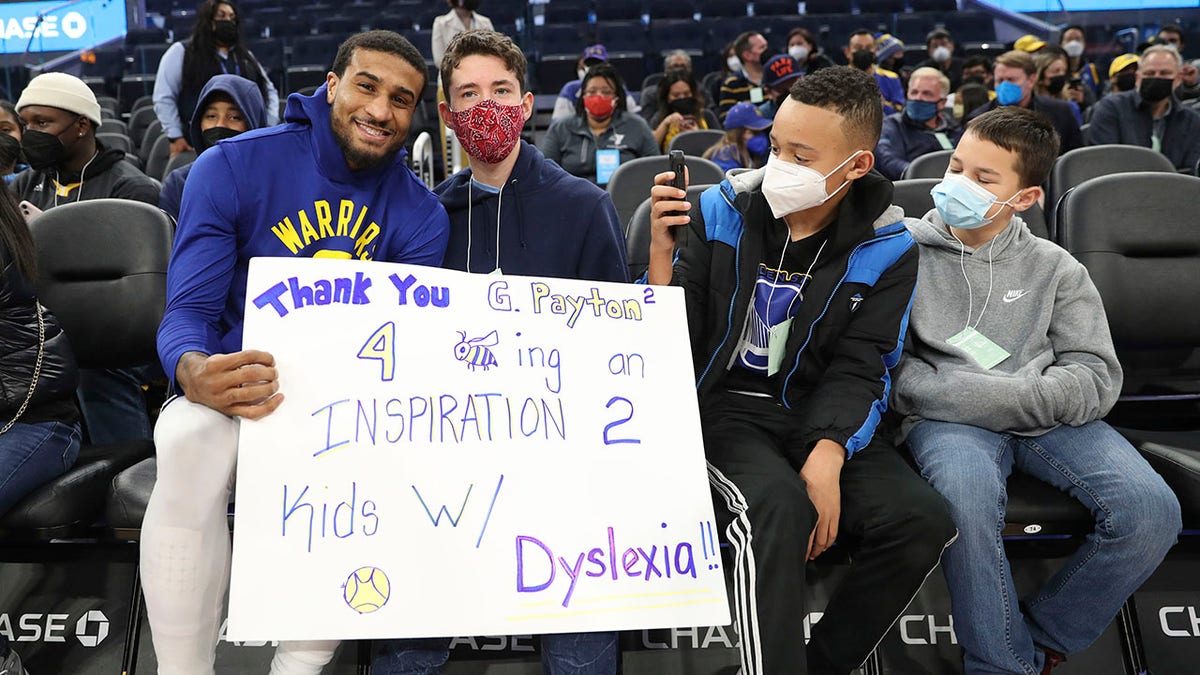 FILE - Golden State Warriors guard Gary Payton II, left, greets young fans from the group Decoding Dyslexia California, before the team's NBA basketball game against the Detroit Pistons in San Francisco, Tuesday, Jan. 18, 2022. Warriors guard Gary Payton II faced daunting challenges reading as a boy because of dyslexia that was diagnosed in second grade. He's now an NBA star with Golden State and he's finding ways to support Bay Area youth with similar learning disabilities to give them tools and courage to push forward when everything feels hard.