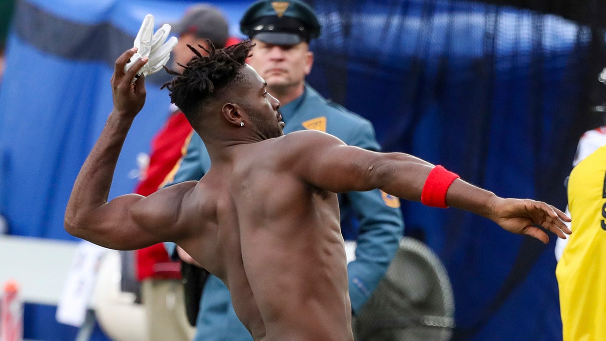A N.J. State Police trooper, background, watches as Tampa Bay Buccaneers wide receiver Antonio Brown throws his gloves into the stands while his team's offense is on the field against the New York Jets during the third quarter of an NFL football game Sunday, Jan. 2, 2022, in East Rutherford, New Jersey.