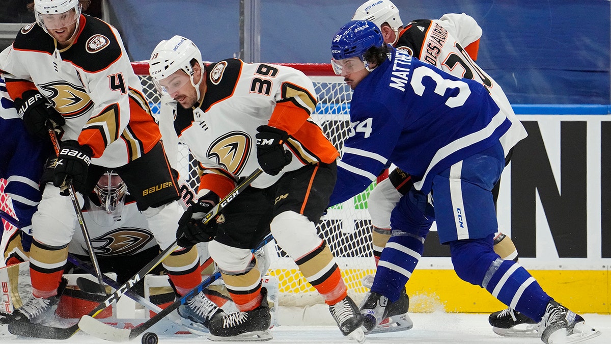 Anaheim Ducks' Sam Carrick (39) and Toronto Maple Leafs' Auston Matthews (34) look for the loose puck during the first period of an NHL hockey game in Toronto on Wednesday, Jan 26, 2022.