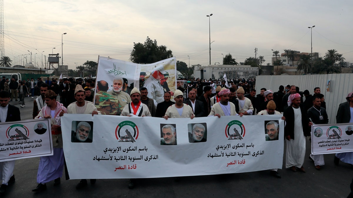 Supporters and members of the Popular Mobilization Forces hold posters of a powerful Iranian general and a top Iraqi militia leader in Baghdad, Iraq, Saturday, Jan. 1, 2022. 