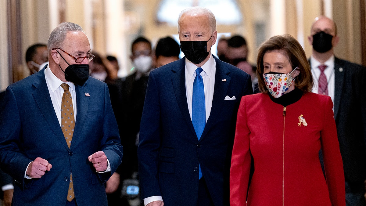 President Biden walks with Senate Majority Leader Chuck Schumer of N.Y., left, and House Speaker Nancy Pelosi of Calif., right.