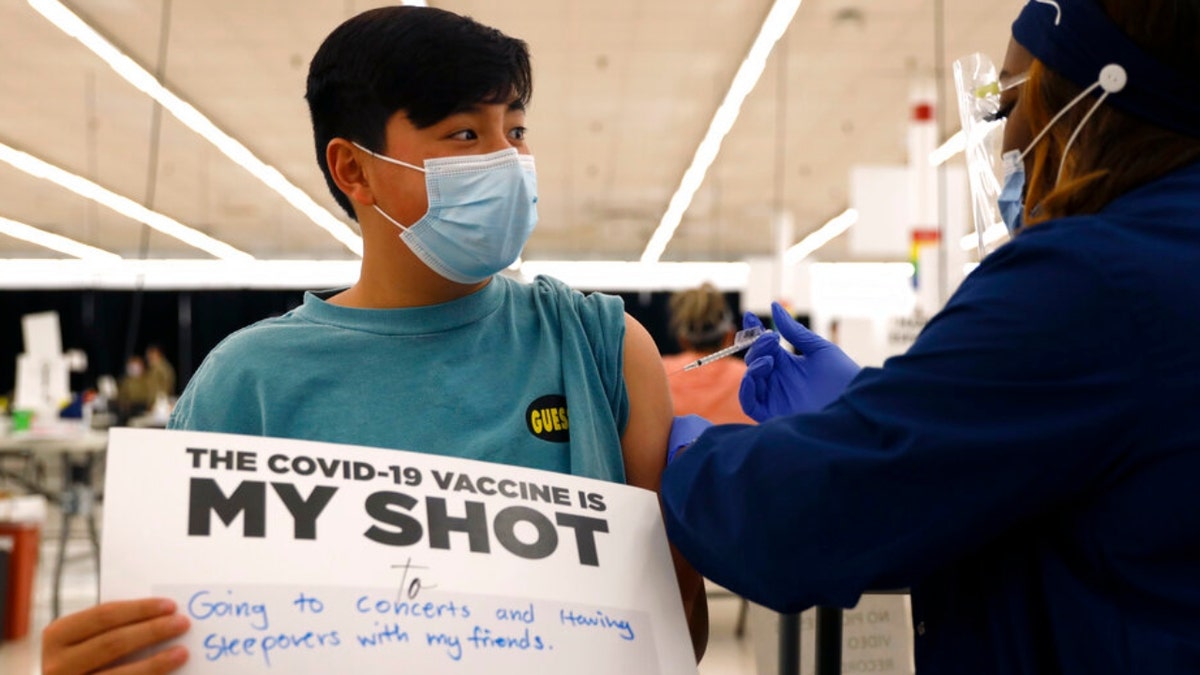 Lucas Kittikamron-Mora, 13, holds a sign in support of COVID-19 vaccinations as he receives his first Pfizer vaccination at the Cook County Public Health Department, May 13, 2021 in Des Plaines, Ill.