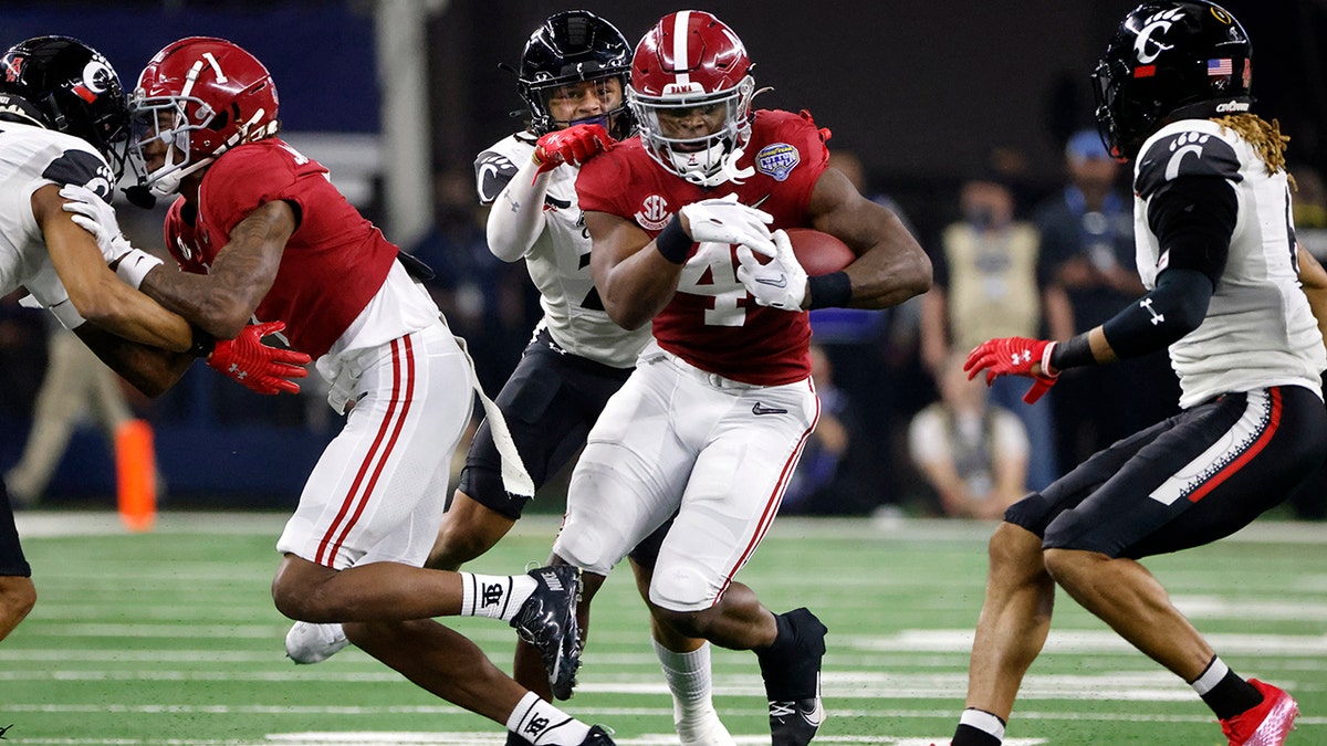 Alabama running back Brian Robinson Jr. (4) runs for a first down as Cincinnati linebacker Deshawn Pace reaches from behind to tackle him during the first half of the Cotton Bowl NCAA College Football Playoff semifinal game, Friday, Dec. 31, 2021, in Arlington, Texas. Alabama won 27-6.