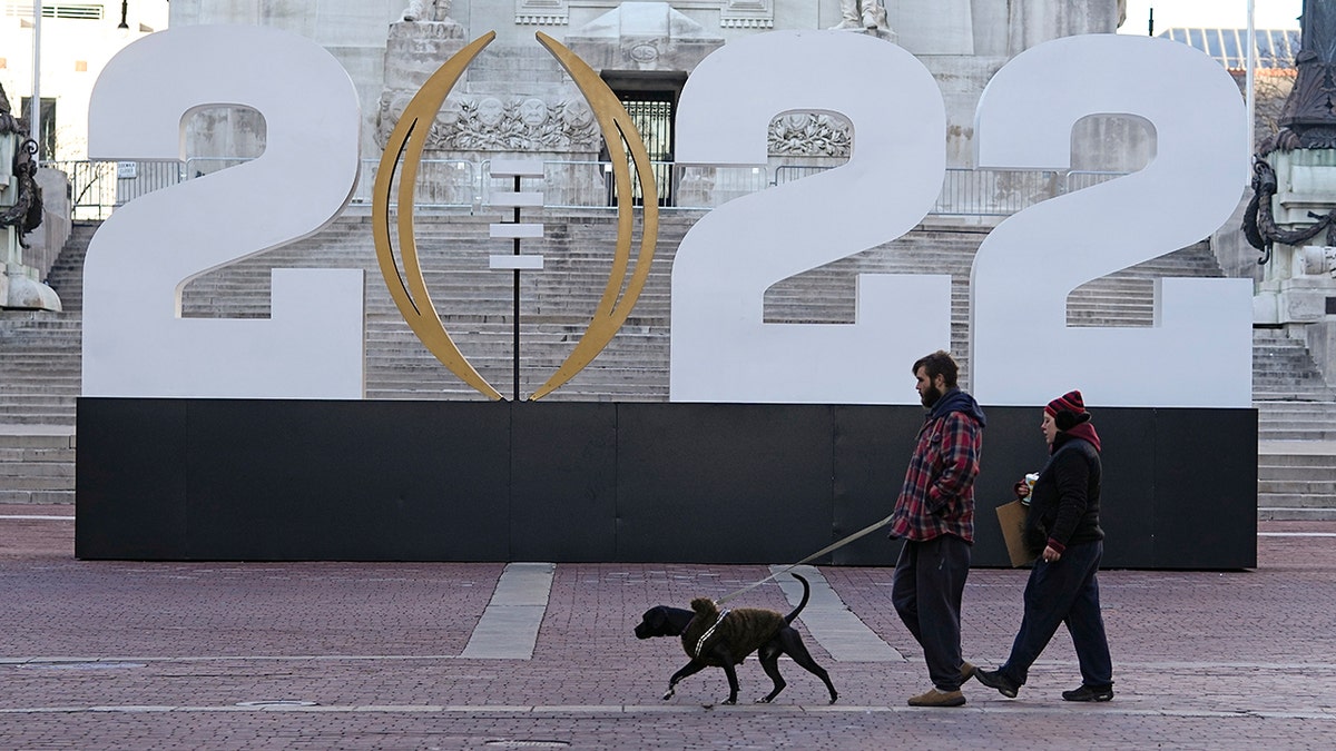 Patrons walk past the College Football Playoff National Championship display on Monument Circle, Friday, Jan. 7, 2022, in Indianapolis. Alabama and Georgia are scheduled to play in the championship game on Jan. 10 at Lucas Oil Stadium.