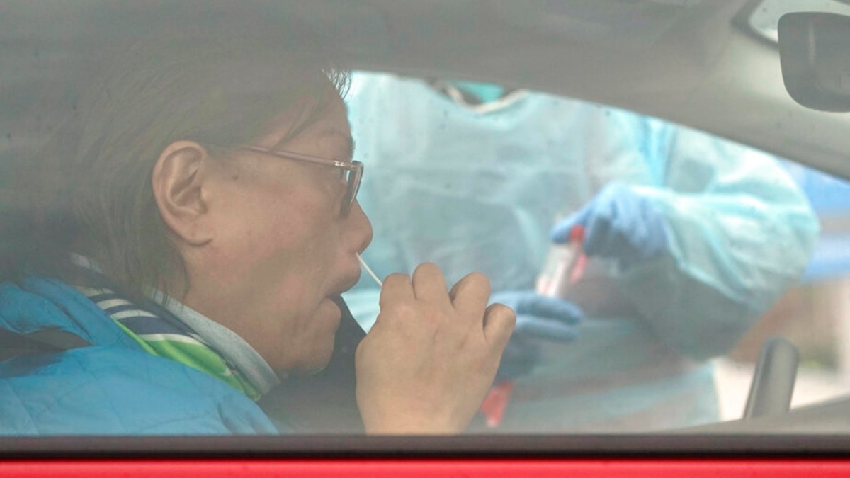 Erick Ramos, of Tacoma, uses a nose swab at a drive-up COVID-19 testing clinic