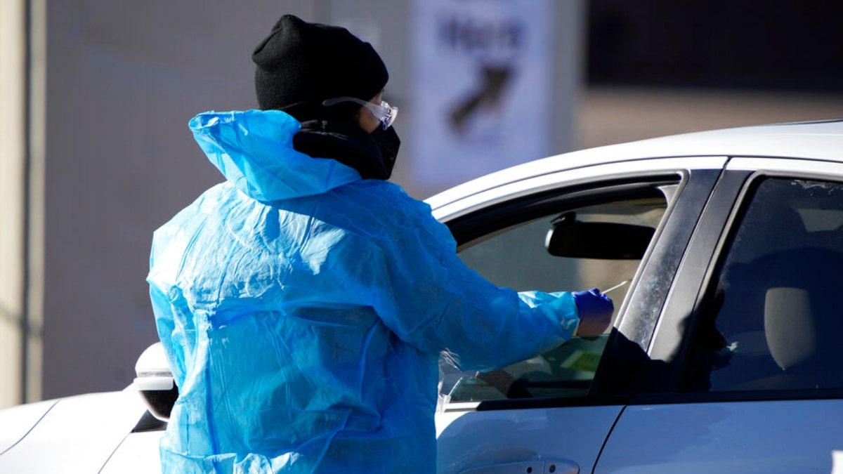 A medical technician performs a nasal swab test on a motorist queued up in a line at a COVID-19 testing site near All City Stadium Thursday, Dec. 30, 2021, in southeast Denver.  (AP Photo/David Zalubowski)