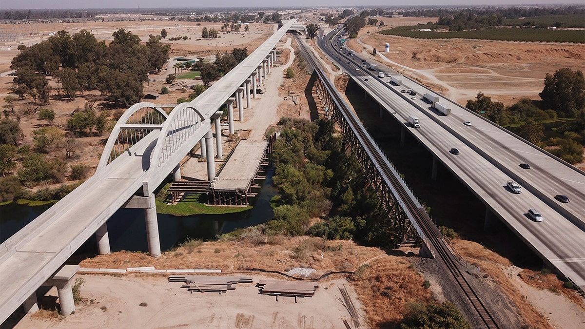In this aerial image taken on Aug. 26, 2021, vehicles drive past farmland and part of the California High Speed Rail Authority San Joaquin River viaduct construction project alongside U.S. Highway 99 through the Central Valley between Madera County and Fresno County, California. 