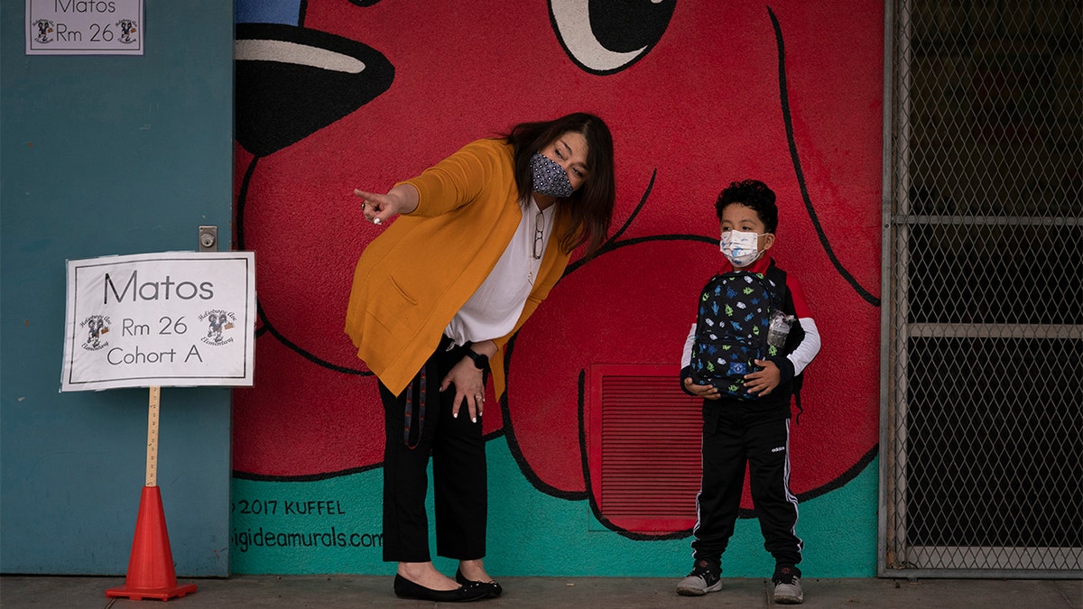 Kindergarten teacher Lilia Matos and her student Jesus Mendez stand outside their classroom on the first day of in-person learning at Heliotrope Avenue Elementary School in Maywood, California, Tuesday, April 13, 2021.