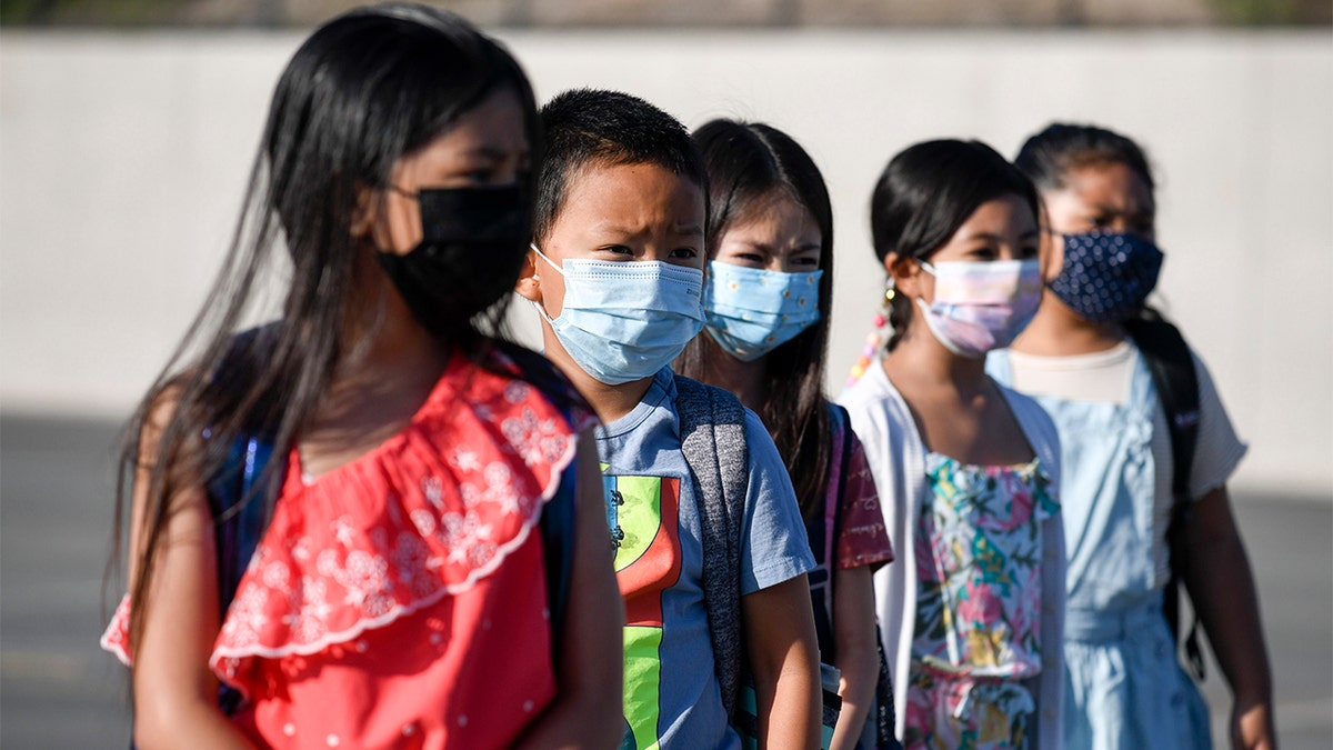Alunos mascarados esperam para serem levados às suas salas de aula na Escola Primária Enrique S. Camarena, quarta-feira, 21 de julho de 2021, em Chula Vista, Califórnia. 