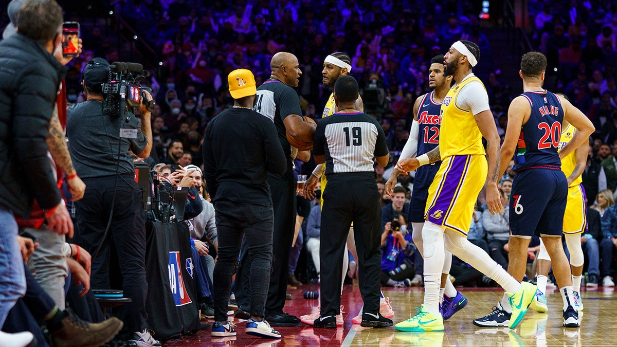 Los Angeles Lakers' Carmelo Anthony, top center, is held back by officials after having a word with a fan in the stands during the second half of an NBA basketball game against the Philadelphia 76ers, Thursday, Jan. 27, 2022, in Philadelphia.