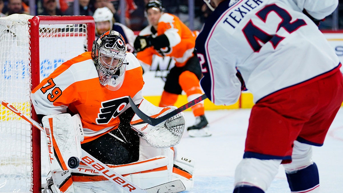 Philadelphia Flyers' Carter Hart, left, blocks a shot by Columbus Blue Jackets' Alexandre Texier during the first period of an NHL hockey game, Thursday, Jan. 20, 2022, in Philadelphia.