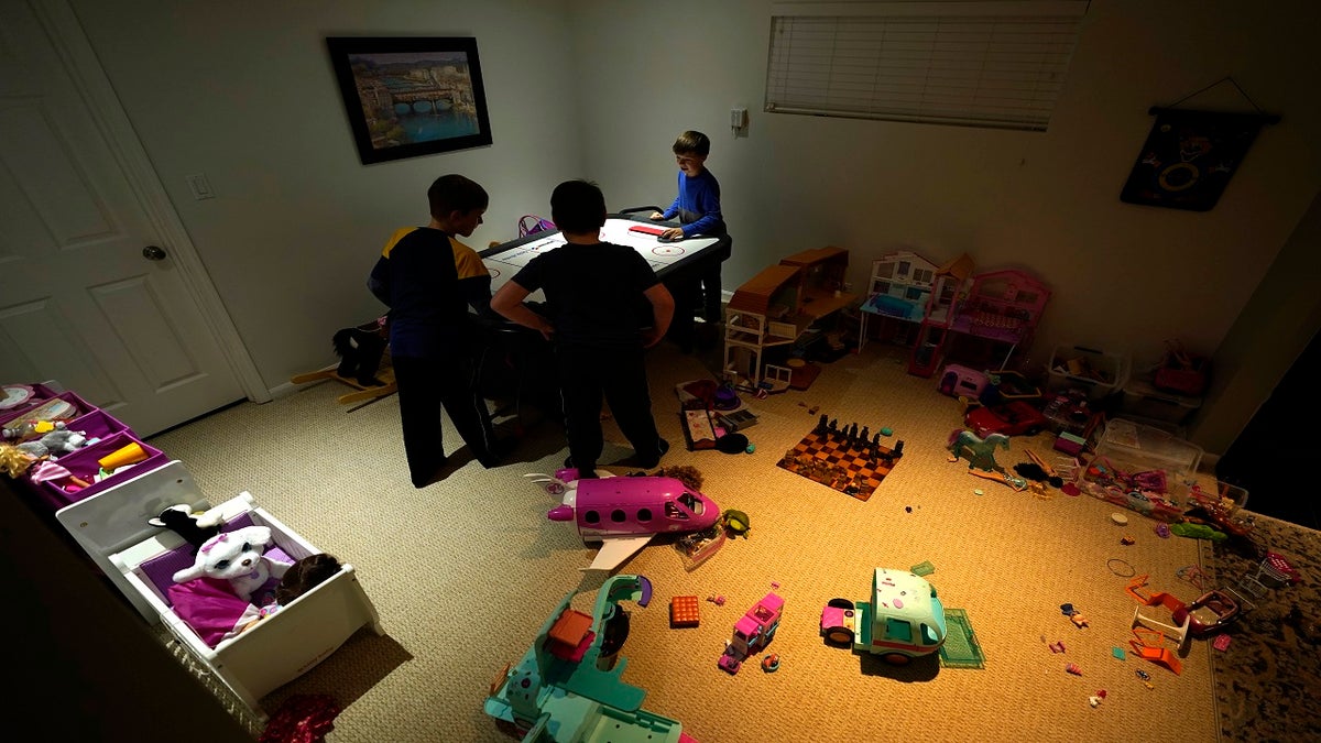 Mick Leichenko, center, entertains his friends Jack and Will Marrion in his Chicago home on Jan. 6, 2022. Hundreds of thousands of Chicago students remain out of school as leaders of the nation's third-largest school district fail to resolve a deepening clash with its teachers union over COVID-19 safety protocols.