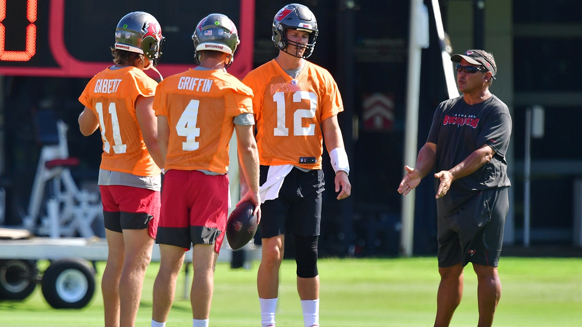 Blaine Gabbert #11, Ryan Griffin #4, and Tom Brady #12 of the Tampa Bay Buccaneers meet with quarterback coach Clyde Christensen during the Buccaneers Mini-Camp at AdventHealth Training Center on June 10, 2021 in Tampa, Florida.