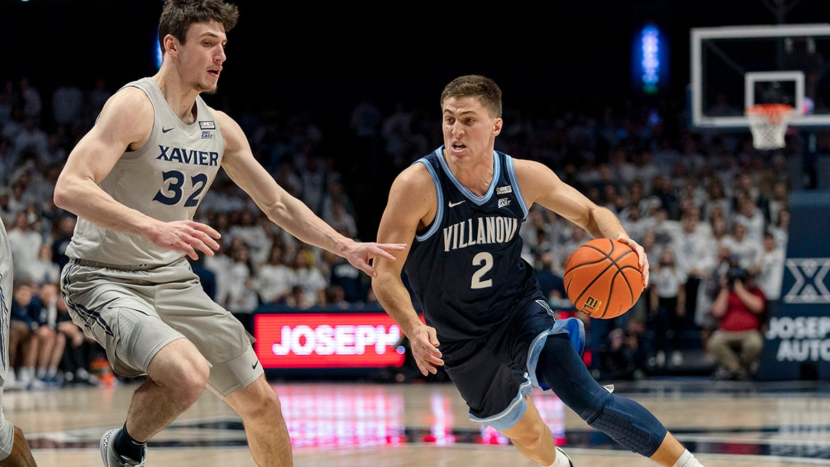Villanova's Collin Gillespie (2) dribbles past Xavier's Zach Freemantle (32) during the first half of an NCAA college basketball game, Wednesday, Jan. 12, 2022, in Cincinnati.