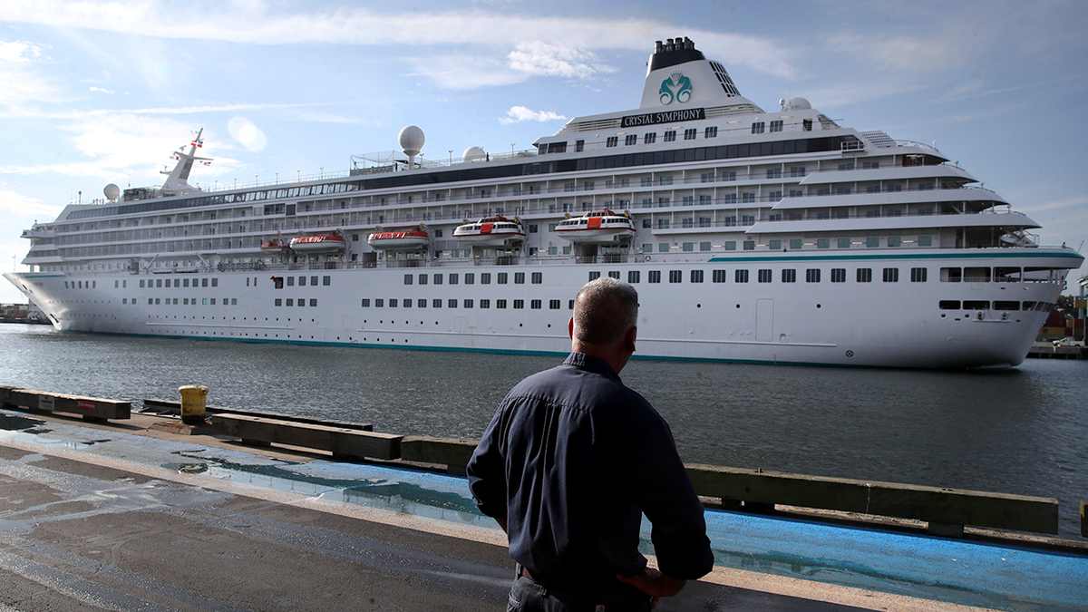 Boston, MA - August 18: A pedestrian watches as the Crystal Symphony cruise ship arrives at Flynn Cruiseport in Boston, MA on August 18, 2021. The ship is scheduled to depart Sunday for a weeklong trip to Bermuda. 