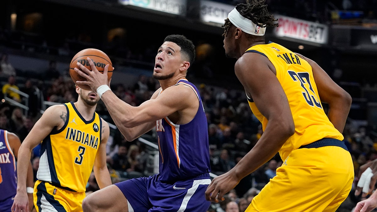 Phoenix Suns' Devin Booker goes to the basket against Indiana Pacers' Myles Turner (33) during the second half of an NBA basketball game, Friday, Jan. 14, 2022, in Indianapolis.