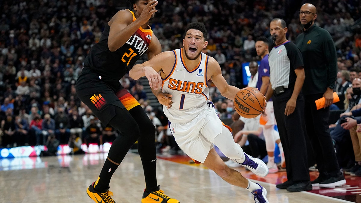Phoenix Suns guard Devin Booker (1) drives around Utah Jazz center Hassan Whiteside (21) in the second half during an NBA basketball game Wednesday, Jan. 26, 2022, in Salt Lake City.